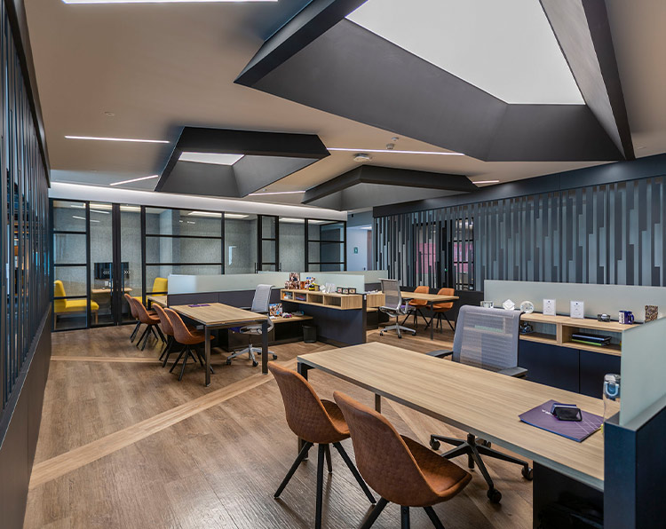 A modern looking workspace with statement geometric light fixtures and linears mounted in the ceiling. Glass walls line the room.