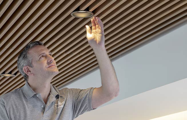 Facility  manager installing light in the ceiling 